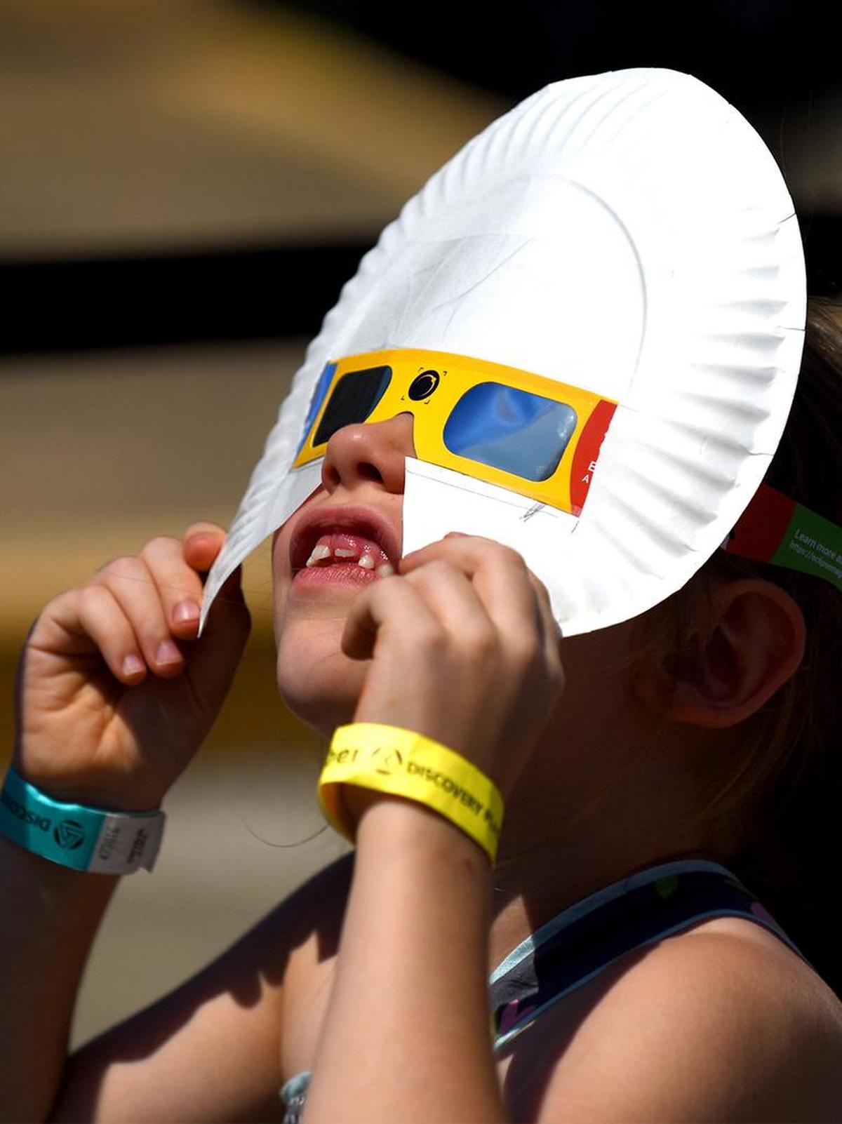 Eden Harwell, de 6 años, de Kings Mountain, Carolina del Norte, observa el eclipse solar desde el estacionamiento del Discovery Place el lunes 21 de agosto de 2017 en Charlotte, Carolina del Norte.