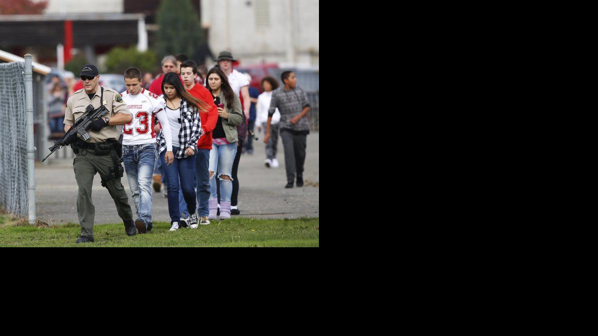 
Un policía armado escolta a estudiantes de Marysville Pilchuck High School, in Marysville, Washington, donde un tiroteo dejo dos muertos y cuatro heridos graves.
