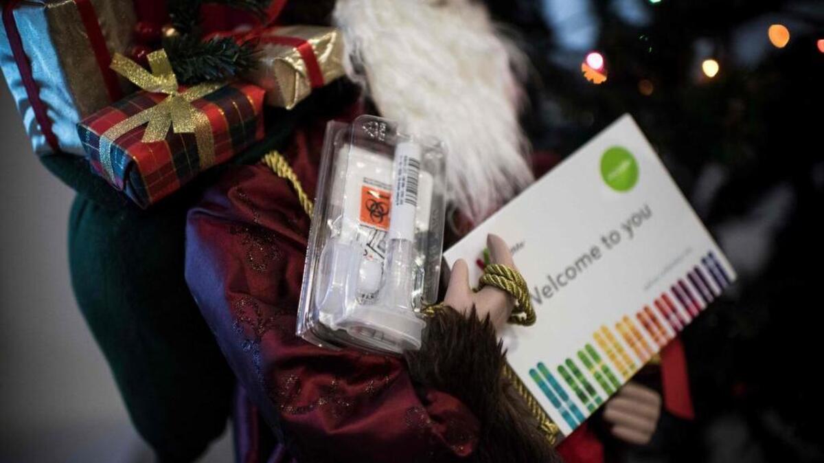 Un kit de recolección de saliva para las pruebas de ADN aparece en los brazos de una muñeco de Papá Noel en Washington, DC el 19 de diciembre de 2018.
