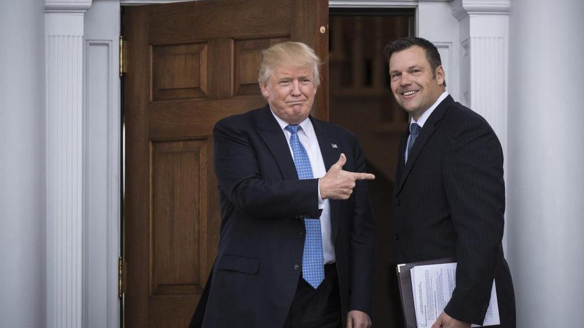 El presidente electo Donald Trump saluda al secretario de Estado de Kansas, Kris Kobach.