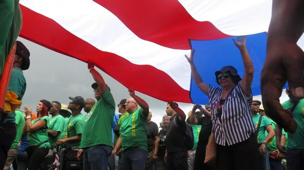 Manifestantes llevan una bandera de Puerto Rico durante una protesta en contra de las medidas de austeridad en la isla, en San Juan, Puerto Rico, el 1ro de mayo.