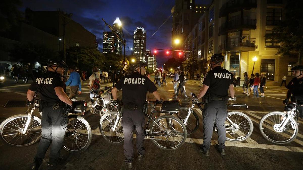 Manifestantes protestan junto a un oficial de policía después que un agente baleara a muerte a Keith Lamont Scott, en Charlotte, Carolina del Norte el miércoles, 21 de septiembre de 2016.