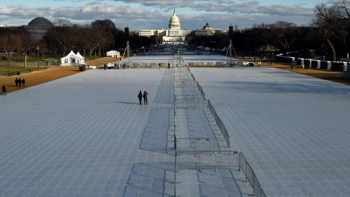 Turistas toman fotos en el National Mall, cubierto con plástico protector y barricadas en Washington, DC el 18 de enero de 2017.