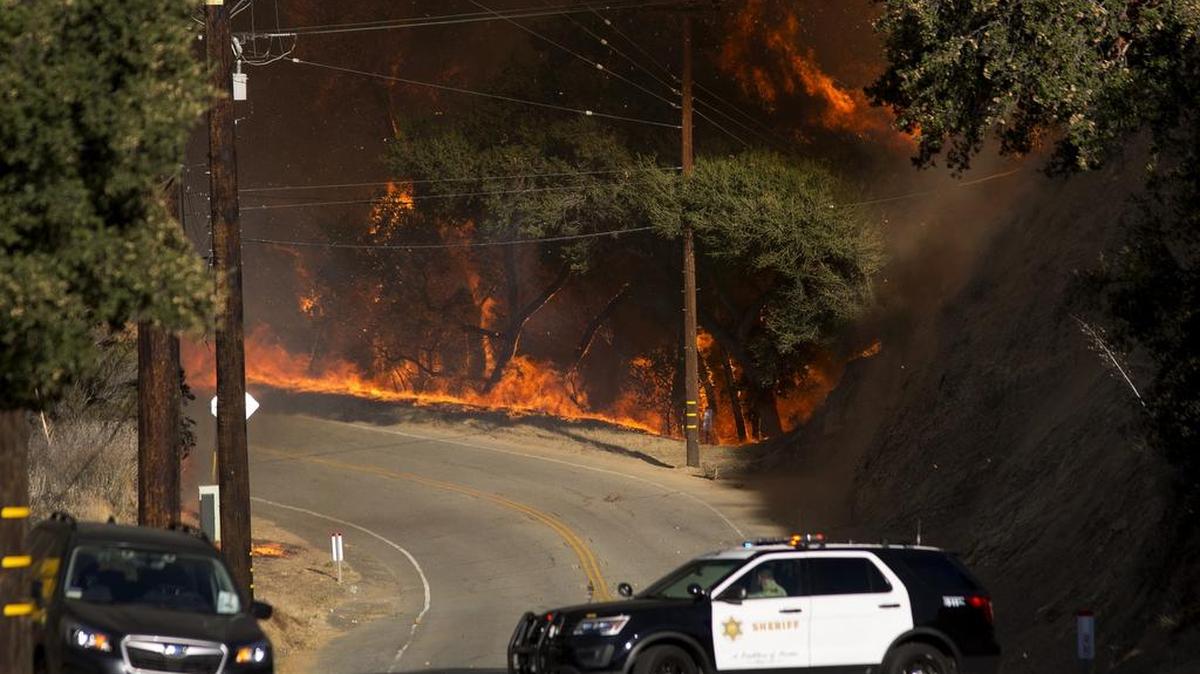 Un policía se aleja de las llamas de “Woolsey Fire” en Malibu Creek State Park, California.