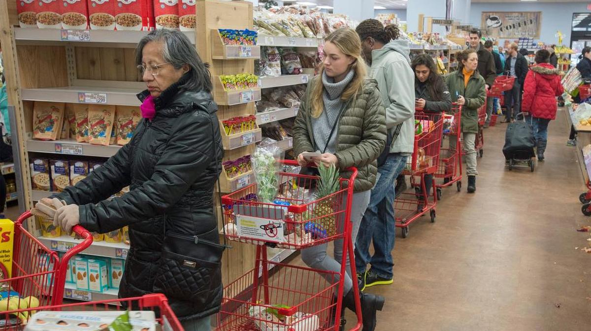 Clientes esperan para comprar víveres ante la proximidad de una tormenta de nieve en Washington DC.