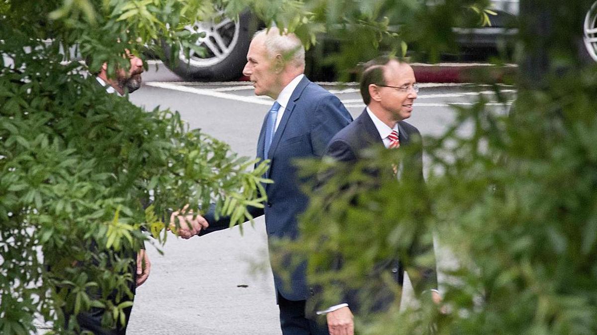 El jefe de gabinete de la Casa Blanca John Kelly estrecha la mano de un hombre no identificado mientras el Asistente del Fiscal General Rod Rosenstein se retira después de una reunión en la Casa Blanca en Washington, DC, el 24 de septiembre de 2018.