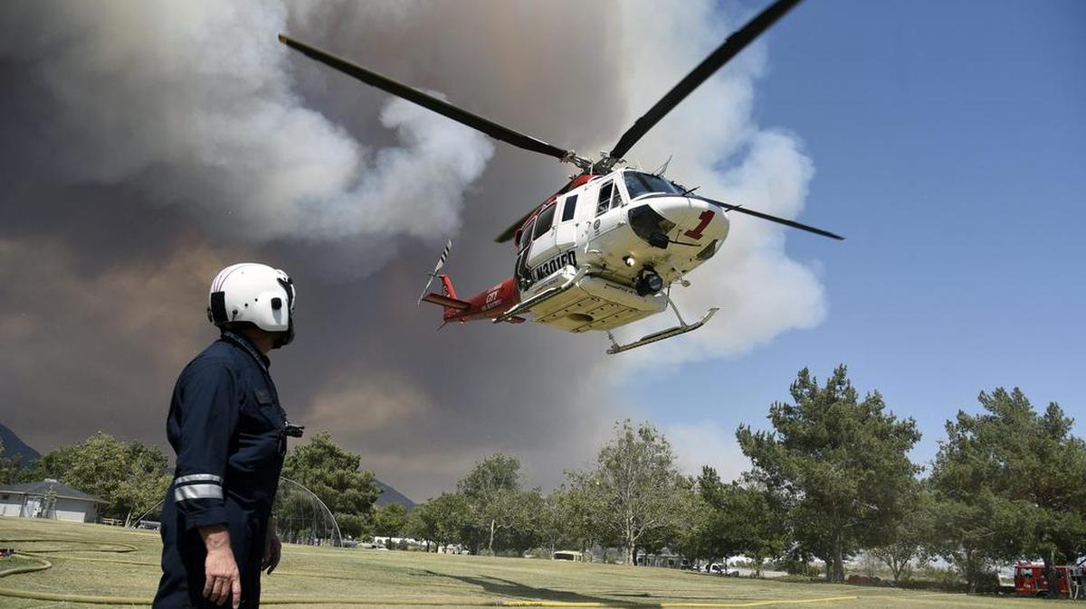 Helicópteros contra incendios del condado de Los Ángeles y personal del cuerpo de bomberos cargan agua para apagar los incendios forestales en 'Fish' cerca del Angeles National Forest, en Duarte, Califonia.