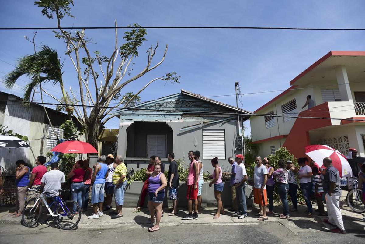 Personas afectadas por el paso del huracán María esperan en línea en el Barrio Obrero para recibir suministros de la Guardia Nacional, en San Juan, Puerto Rico.