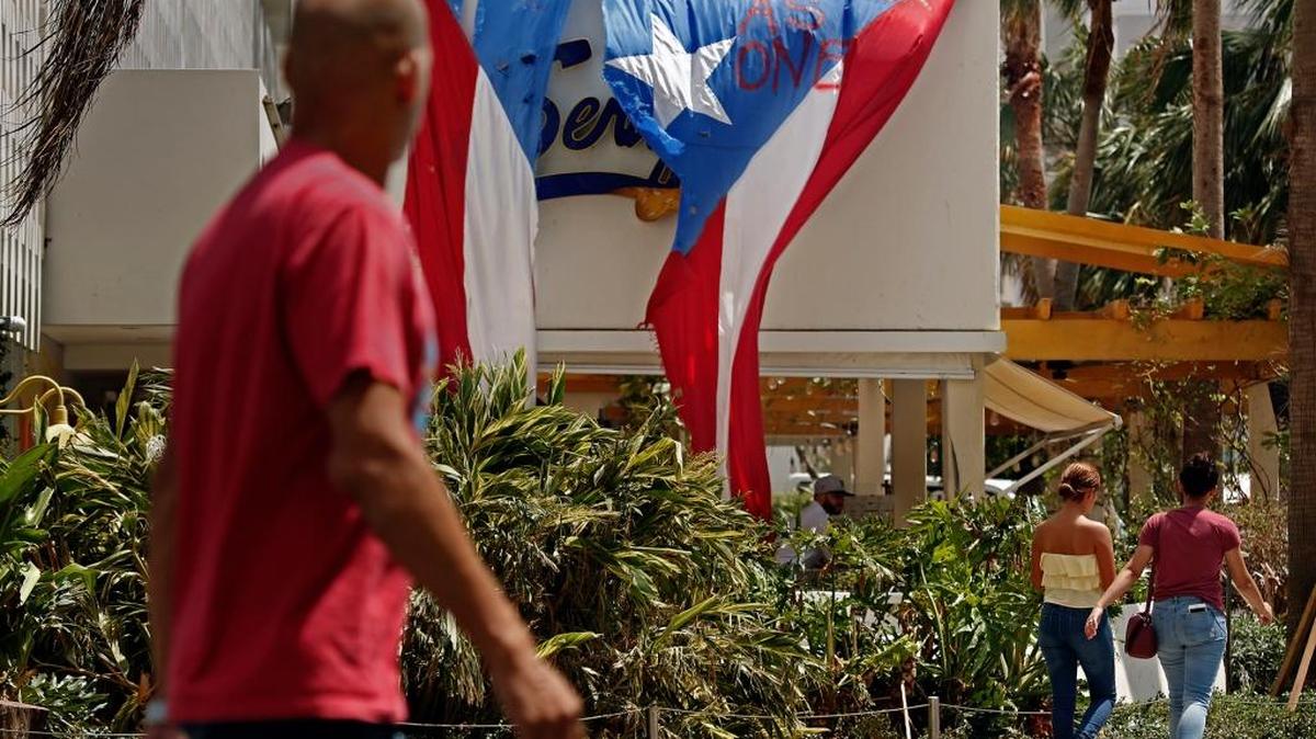 Una persona camina junto a un letrero que dice ‘Together as one’ en el vecindario de Condado, en San Juan, el 2 de octubre.