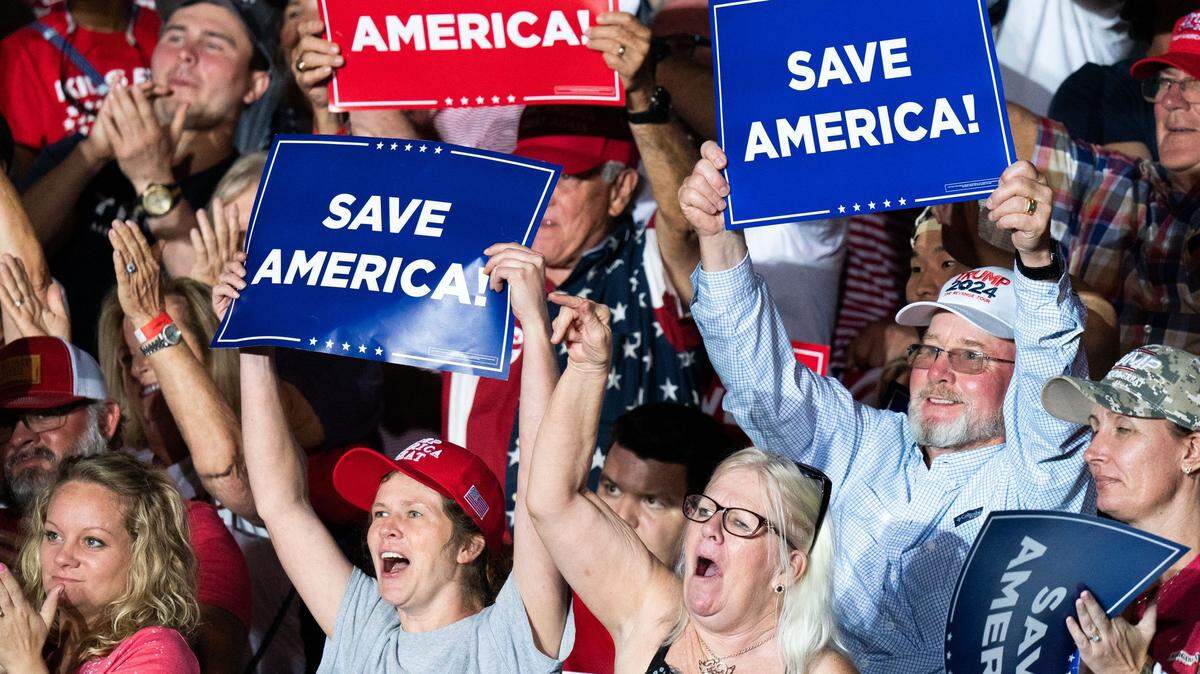 Simpatizantes del expresidente Donald Trump levantan pancartas que dicen “Salven a América”, durante un mitin el sábado 25 de septiembre de 2021, en Perry, Georgia. 