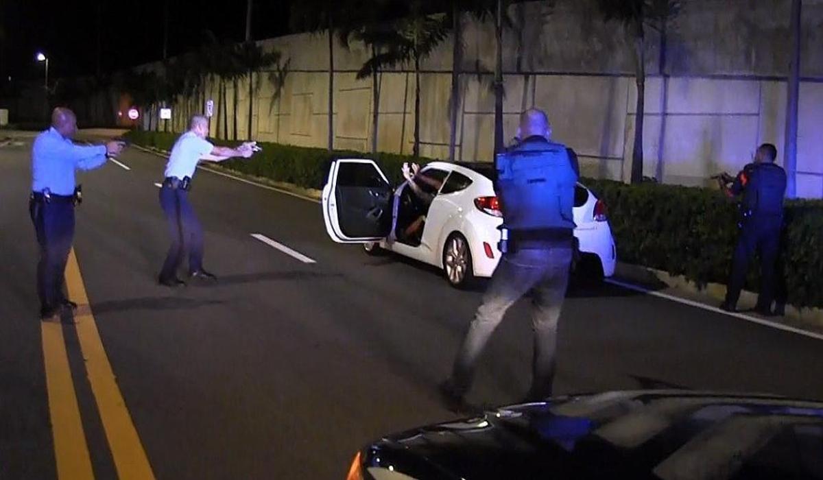 El oficial de policía de Puerto Rico Heriberto Soto, segundo desde la izquierda, grita órdenes al pasajero y al conductor de un vehículo después de la persecución a alta velocidad a través de San Juan el miércoles 18 de octubre de 2017.