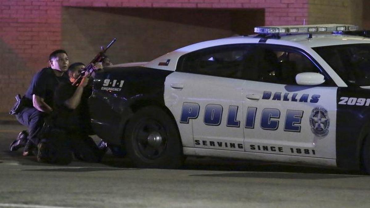 Agentes de policía de Dallas se protegen detrás de una patrulla el jueves, durante un ataque de francotiradores en el centro de la ciudad cuando se realizaba una protesta.