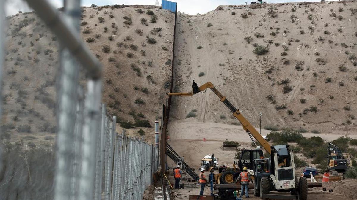Trabajadores continúan las labores para levantar una cerca más alta en la zona fronteriza entre México y EEUU.
