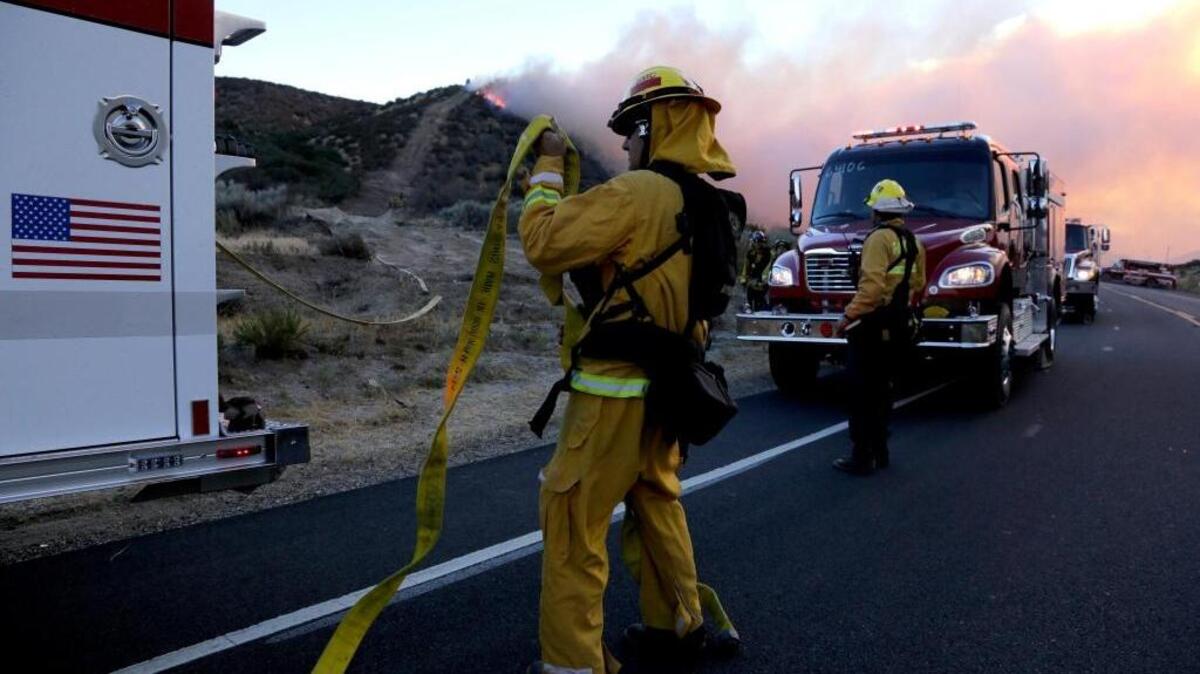 Bomberos trabajan en una vía junto a uno de los focos del gran incendio forestal al norte de Los Ángeles.