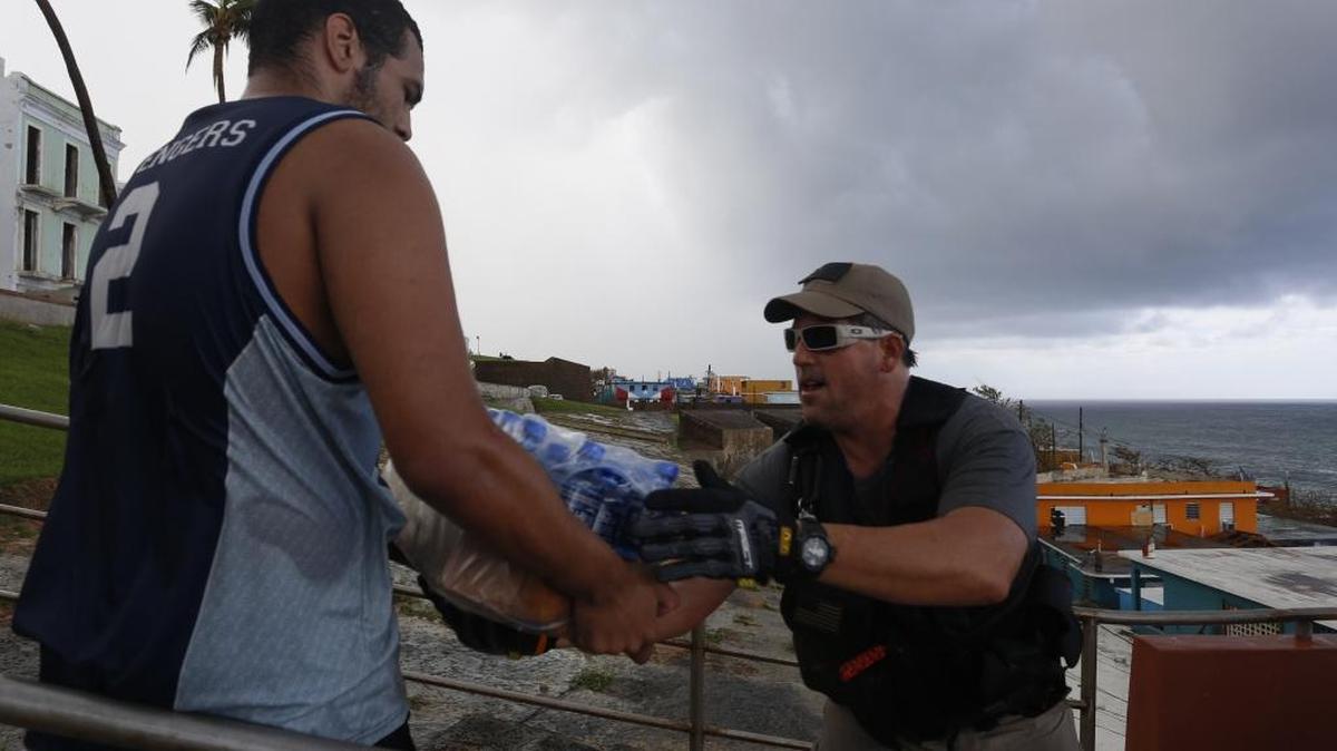 Dos hombres trasladan suministros en la comunidad de vecinos La Perla, un barrio costero de San Juan, Puerto Rico,el 29 de septiembre de 2017 tras el paso del huracán María.