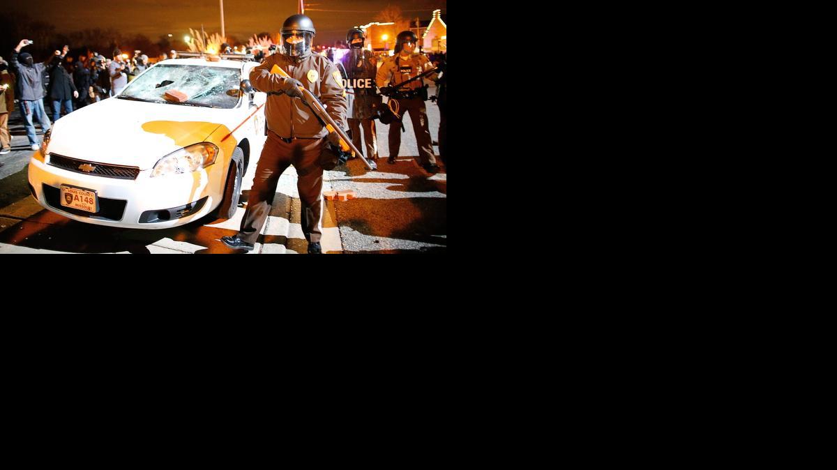 
Policías antimotines permenecen cerca a un vehículo destruido por manifestantes durante enfrentamientos este 24 de noviembre de 2014, en Ferguson (EE.UU.).EFE/LARRY W. SMITH
