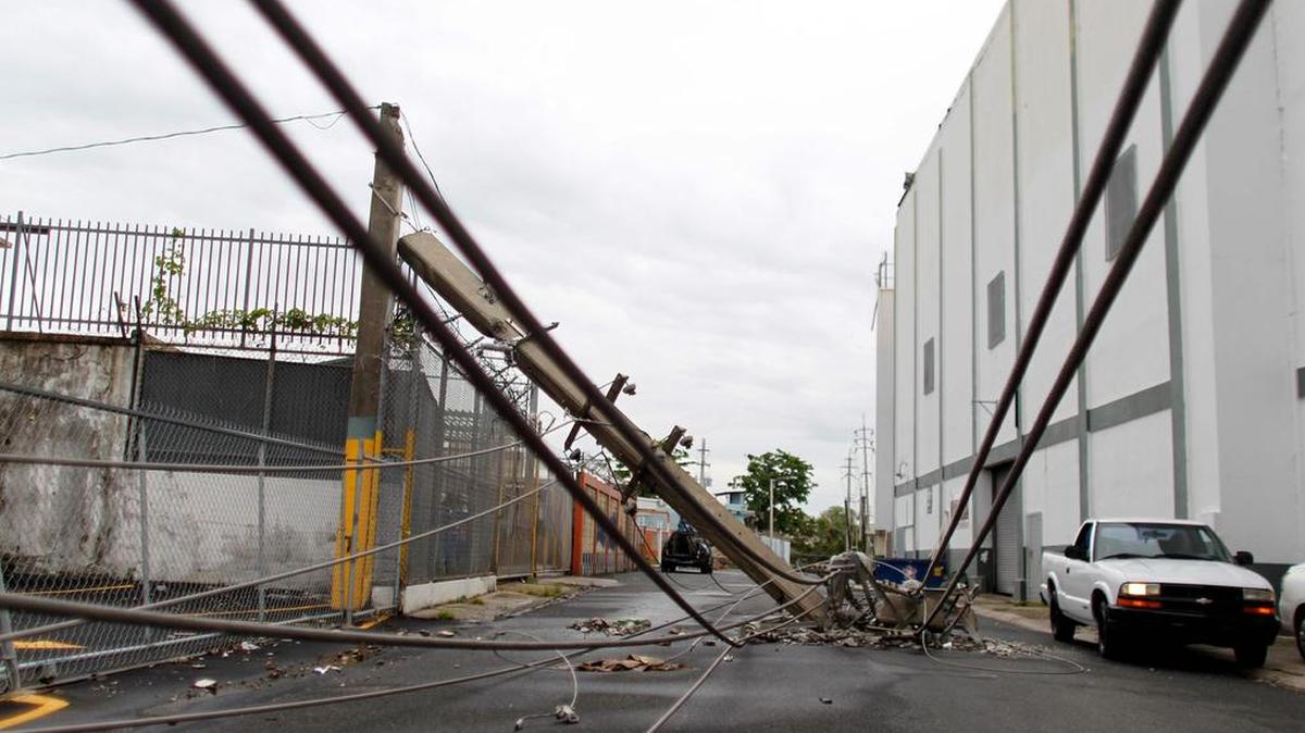 Un automóvil conduce junto a postes de la línea eléctrica caídos por el paso del huracán María en San Juan, Puerto Rico el 7 de noviembre de 2017.