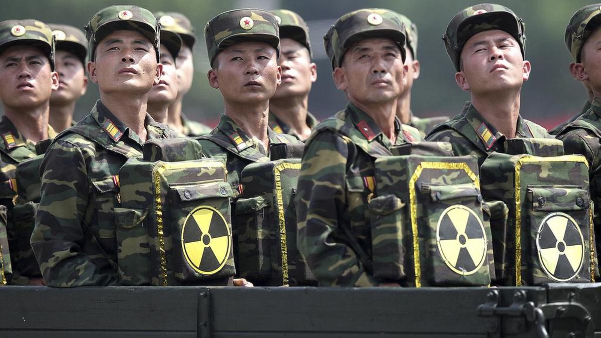 En esta foto del 27 de julio de 2013, los soldados de Corea del Norte se vuelven y miran hacia su líder Kim Jong Un desde un vehículo de desfile militar mientras llevan paquetes marcados con el símbolo nuclear durante una ceremonia que conmemora el 60 aniversario del armisticio de Corea en Pyongyang , Corea del Norte.