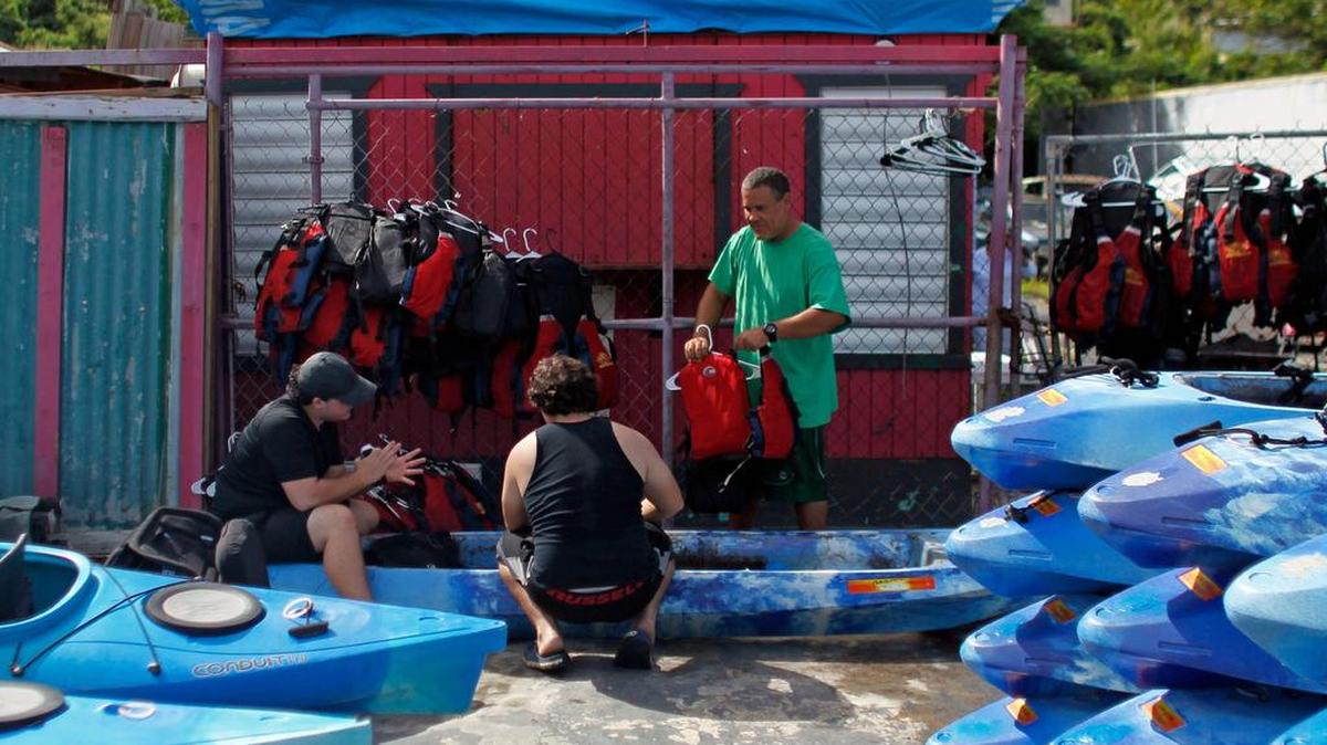 José Figueroa limpia kayaks y equipos con la ayuda de dos de sus compañeros de una compañía local que ofrece paseos en kayak en Fajardo Puerto Rico el 25 de noviembre de 2017.