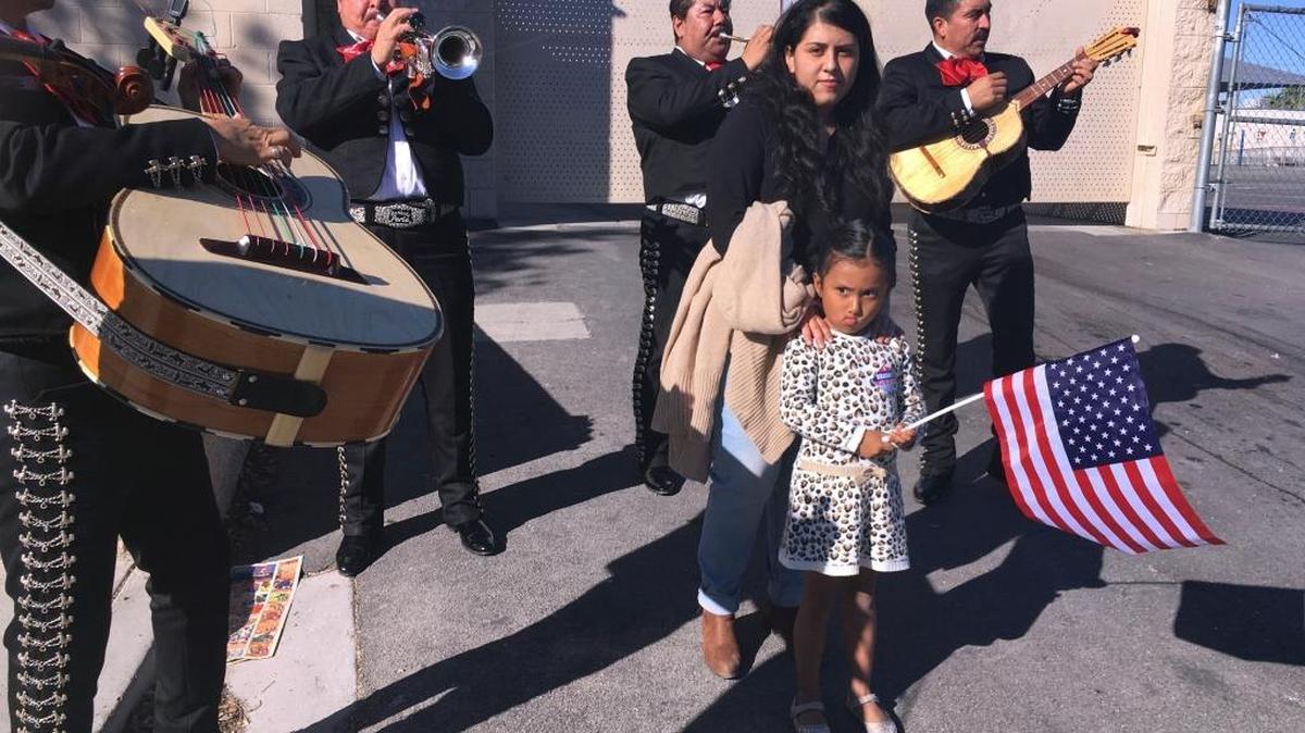 Jacqueline Lima, de 20 años, camina con su hermanita de cuatro años de edad con la bandera de Estados Unidos y en medio de una serenata de mariachis después de que Lima ejerciera el voto por primera vez.