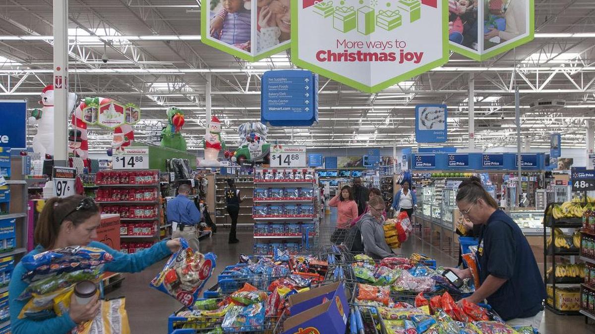 Clientes de Walmart escojan dulces en rebaja por Halloween en lo que empleados los separan por precios, en una de las tiendas de de la compañía en Dallas.