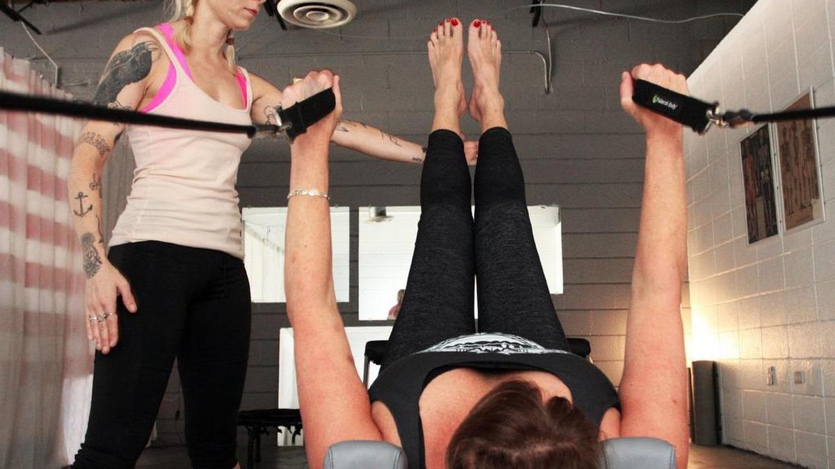 La entrenadora Stella Wingfield Cook, que maneja su propio gimnasio, auxilia a una clienta en las rutinas.