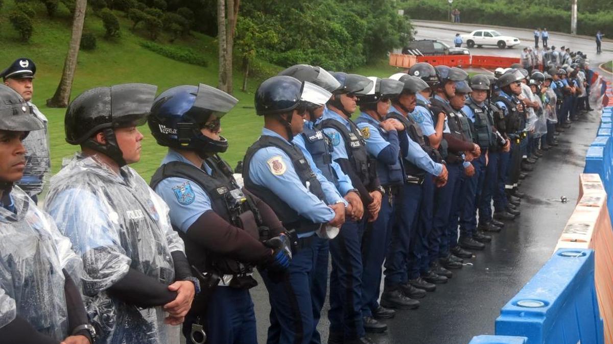 Policías forman el viernes una barrera contra puertorriqueños que protestan la Junta de Control Federal, en San Juan.