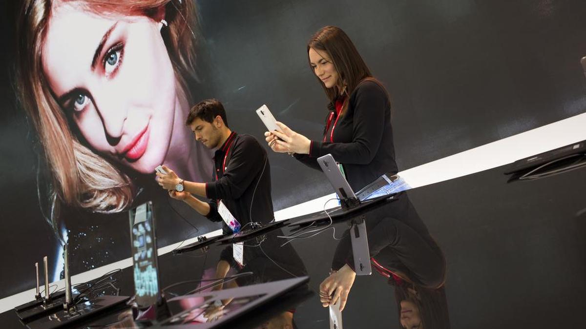 Participantes en el Congreso Mundial de Móviles en Barcelona inspeccionan el nuevo teléfono inteligente Huawei.
