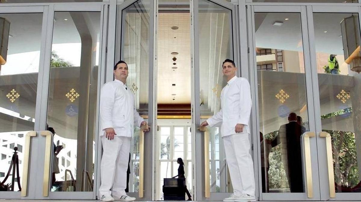 Los porteros Yandy López, (izq.) y Félix Alpizar, abren las puertas a los huespedes en la entrada del hotel Faena, que inició operaciones el martes.