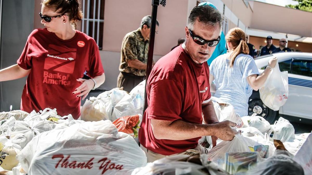 Gene Schaefer, el presidente de mercados de Miami del Bank of America, y la vicepresidenta Ashley Hays, realizan trabajo de voluntarios en la entrega de alimentos.