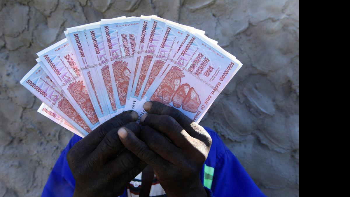
Un hombre muestra billetes de 500,000 millones, cada uno equivalente a unos 20 centavos de dólar de EEUU.


