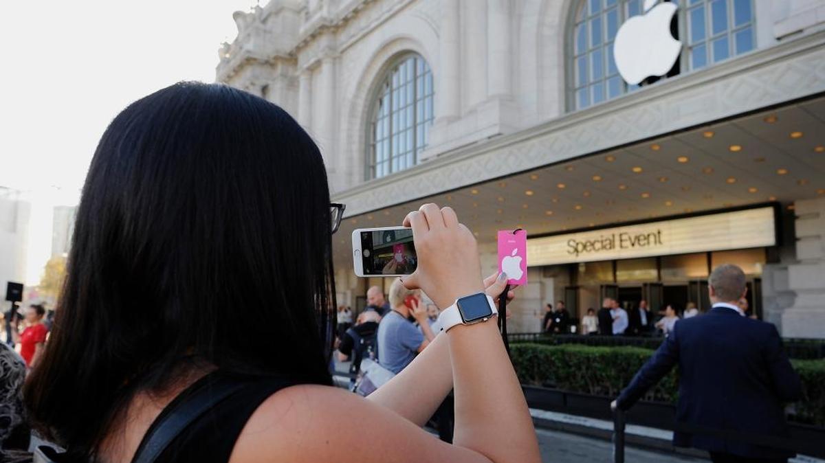 
Una mujer usa su celular para tomar una foto frente al Auditorio Cívico Bill Graham, en San Francisco, antes del inicio de un evento donde Apple Inc. daría a conocer sus nuevos productos.
