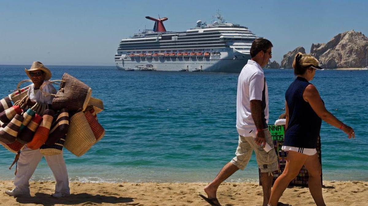 Esta foto de archivo tomada el 15 de mayo de 2012 muestra a turistas caminando en la playa de Medano mientras el Carnival Splendor está anclado en alta mar en Los Cabos, Baja California, México.