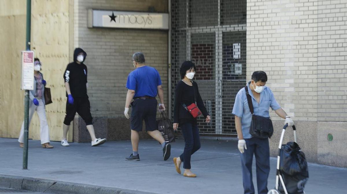 Varias personas pasan el pasado lunes frente a la puerta aún cerrada de una tienda Macy’s en Queens, Nueva York.