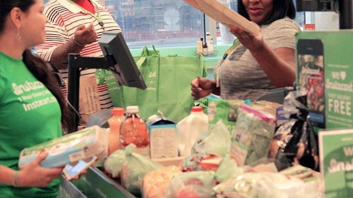 Claudia Rodas (izq.), de Instacart, verifica el pedido de un cliente, mientras Joel King (cen.) y Louna Nelson, completan la orden, en un establecimiento en el downtown de Miami, a inicios de diciembre.