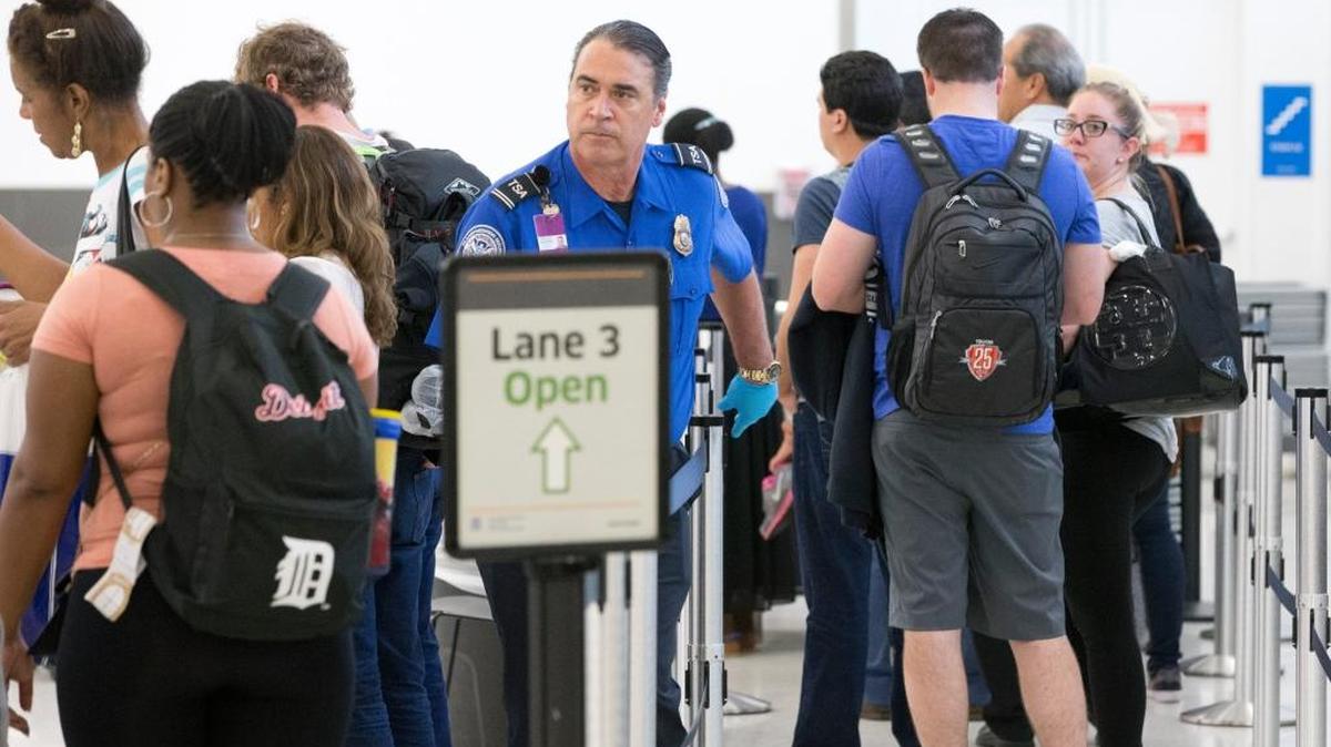 Un agente de la Administración de Seguridad del Transporte ayuda a pasajeros en la línea para ser sometidos a inspección, en el aeropuerto internacional de Fort Lauderdale-Hollywood.
