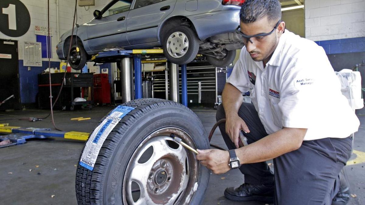 Un mecánico de autos prepara un neumático nuevo para un cliente. Archivo.