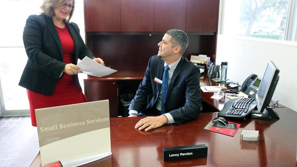 Odalis Martínez, directora de la banca para pequeñas empresas del Bank of America, en Miami, revisa un informe con su asistente Lenny Rendon.