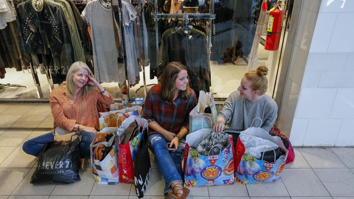 Una mujer con sus dos hijas descansan tras pasar más de siete horas cazando ofertas en Atlanta, durante el “Viernes negro”.
