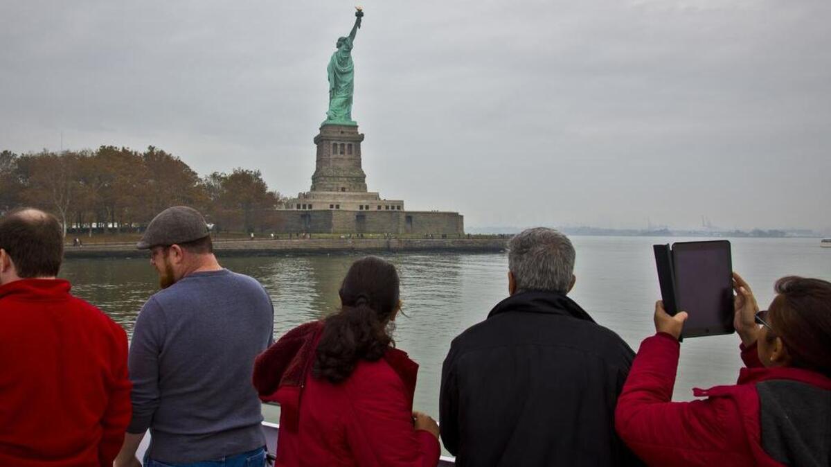 Turistas observan la Estatua de la Libertad desde un ferry en Nueva York. Expertos dijeron el lunes que la industria del turismo de EEUU está afectada.