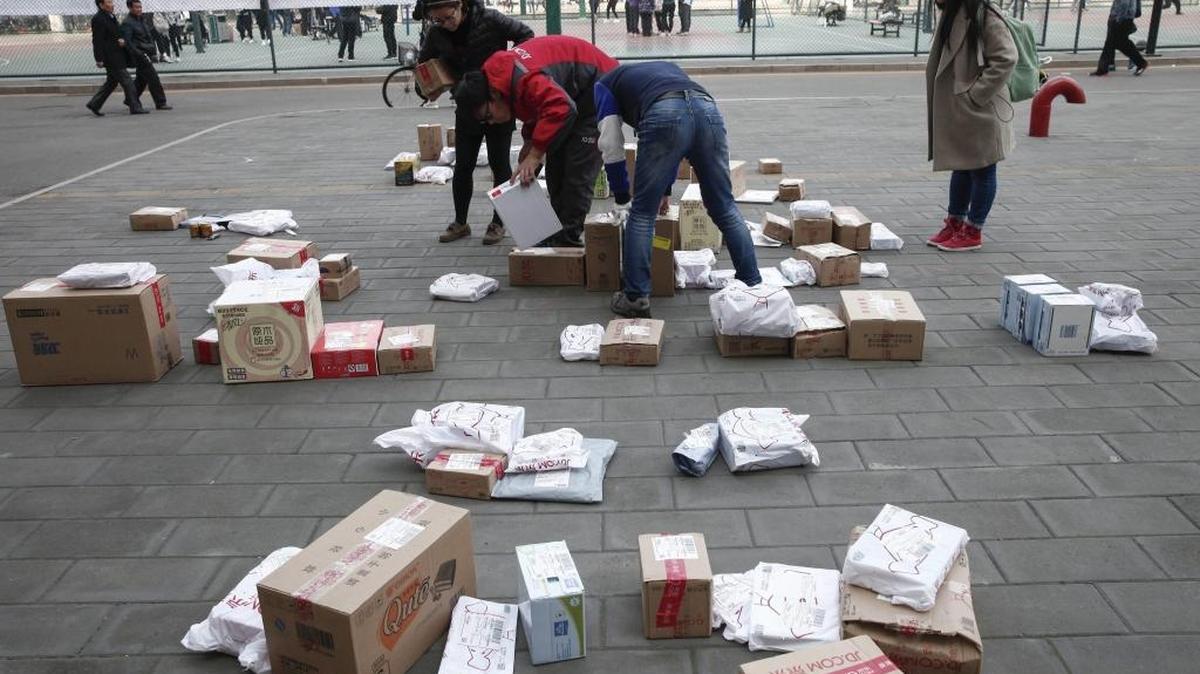 Unos repartidores de una tienda online ayudan el viernes a unas clientas a recoger la mercancía que han pedido por el “Día del Soltero”, en un estacionamiento de Pekín.