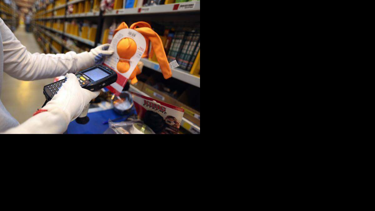 
Un empleado de Amazon usa un scanner para despachar una orden de un cliente. Las tiendas están apurando los pedidos onlina para hacerlos mas apetecibles para los compradores.
