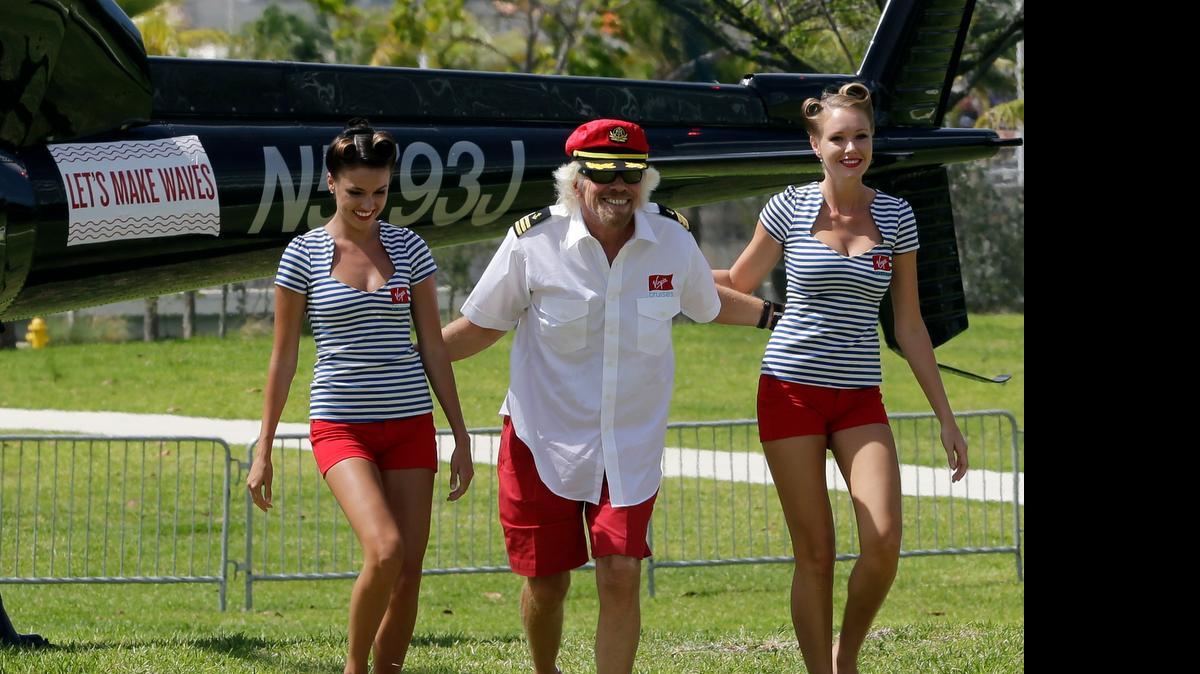 
El excéntrico millonario Richard Branson llegó al Pérez Art Museum de Miami para una rueda de prensa en un helicóptero acompañado de dos modelos vestidas con ajustados trajes marineros.

