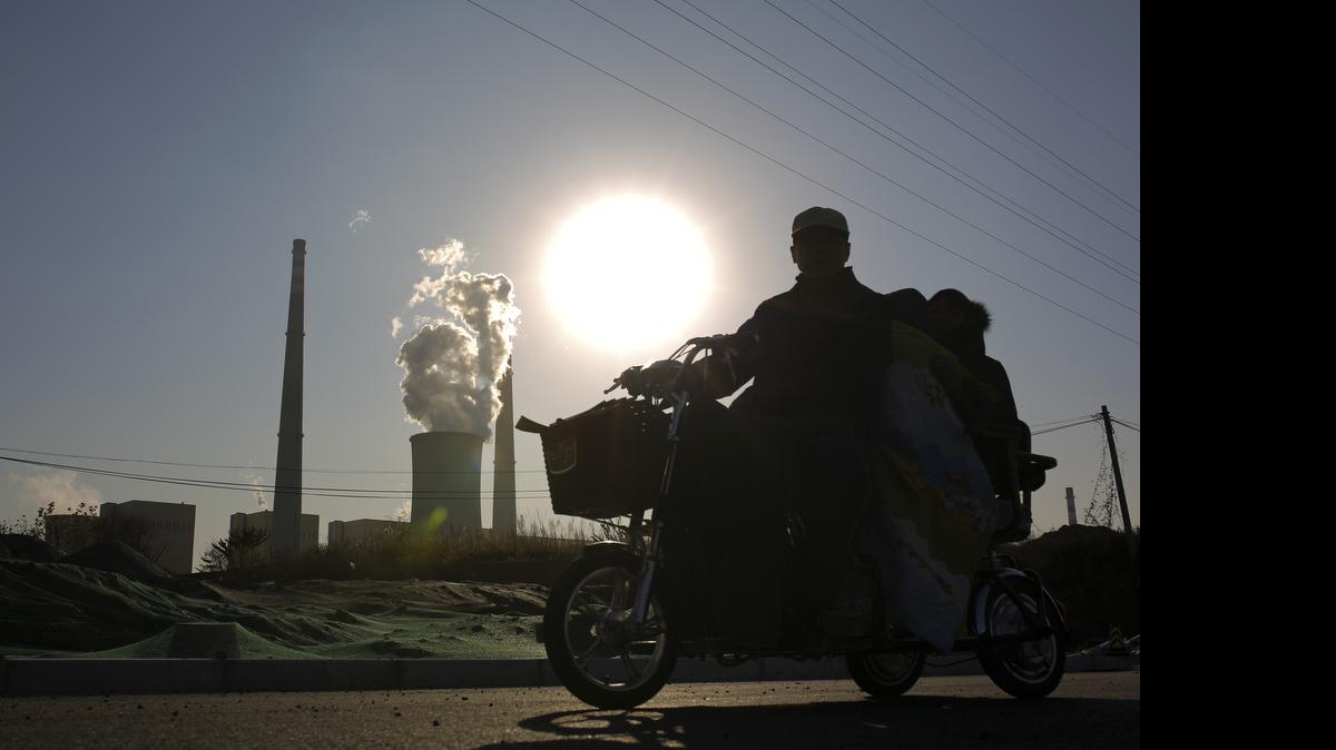 
Una familia china en motocicleta pasa frente a una planta en Pekín. El gobierno chino dice que pondrá en marcha medidas para buscar el equilibrio entre el crecimiento y la reestructuración del tejido productivo.
