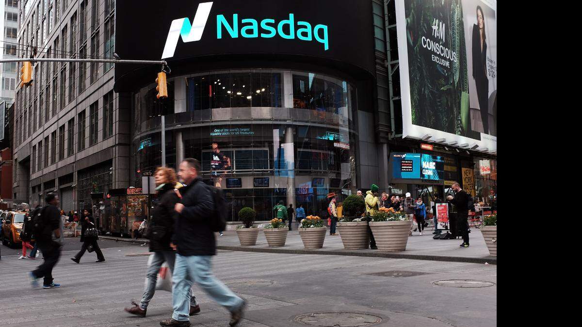 
Dos personas cruzan la calle frente a la pizarra del índice compuesto Nasdaq de valores tecnológicos en Times Square el jueves, luego de batir el récord.
