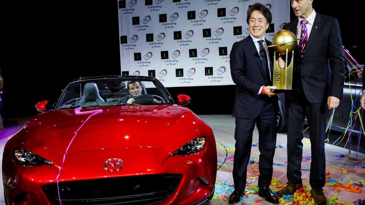 El presidente de Mazda, Masahiro Moro (izq), recibe el trofeo al auto del año 2016 por el Mazda MX-5 en un acto celebrado en el Salón Internacional del Automóvil de NY.