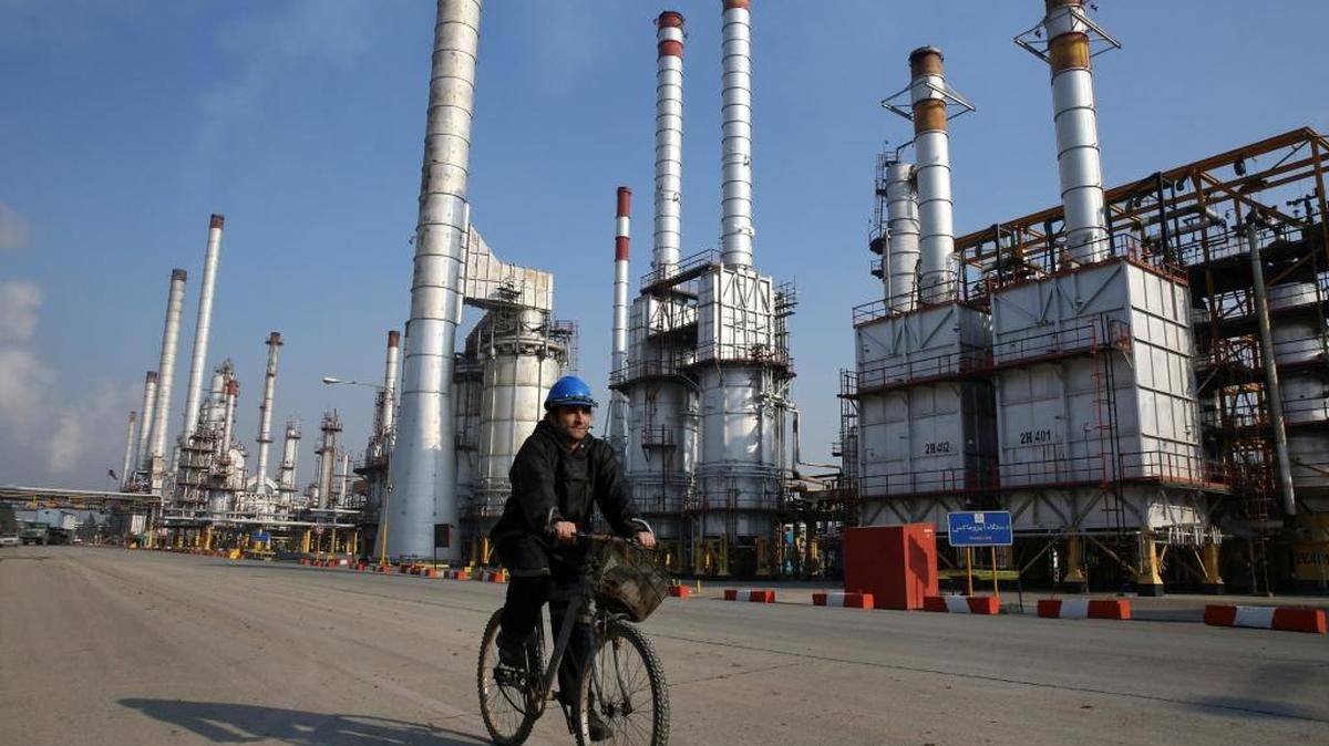 Un trabajador petrolero se desplaza en su bicicleta por la refinería de petróleo en el sur de Teherán, Irán. La producción de petróleo de ese país se ha incrementado en 400,000 barriles al día. Foto de archivo.