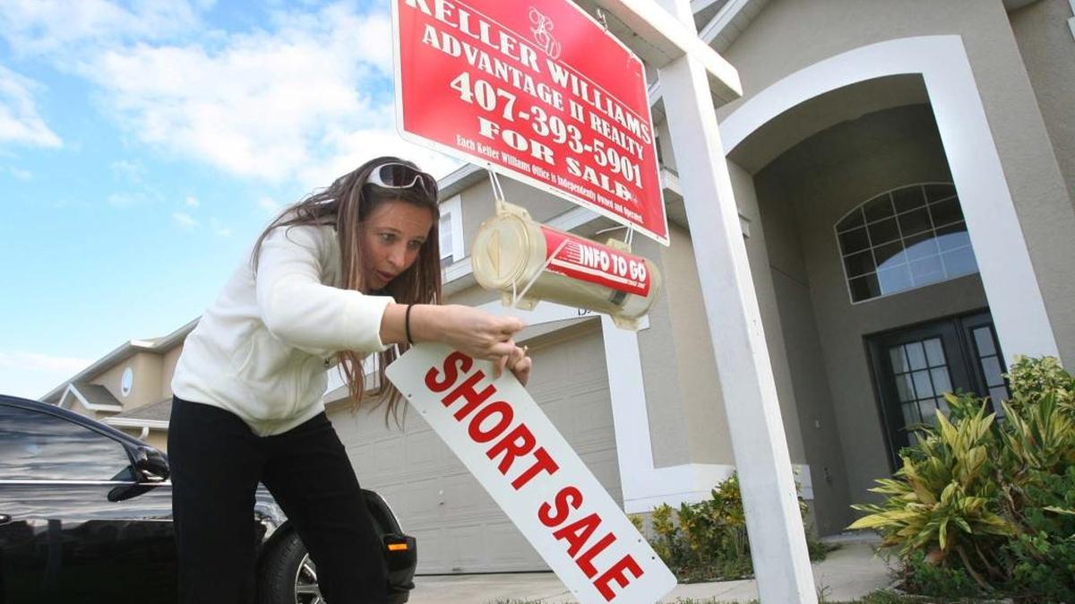 Mysty Stange de la empresa Keller Williams coloca un letrero de “short sale” en una casa en Avalon Park, en Orlando. Foto de archivo.