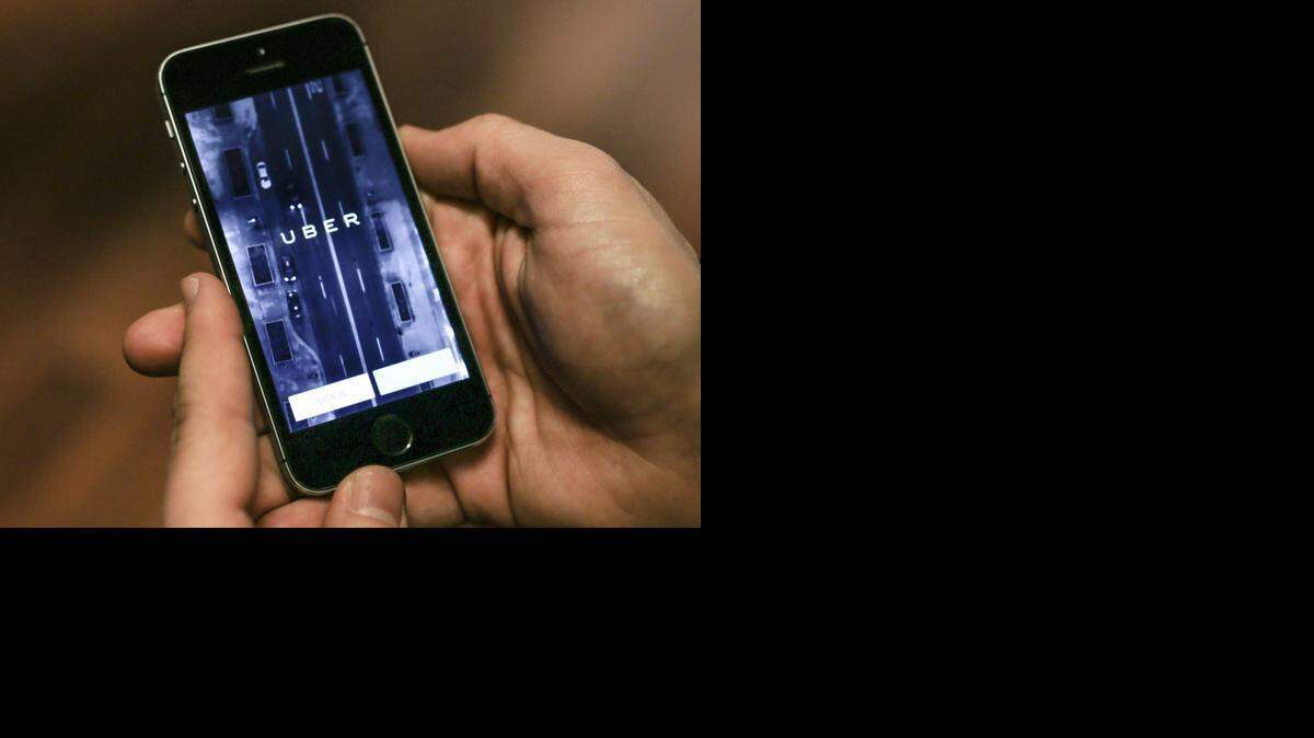 
Una persona muestra la aplicación de Uber, el servicio de autos de alquiler en el teléfono celular.


