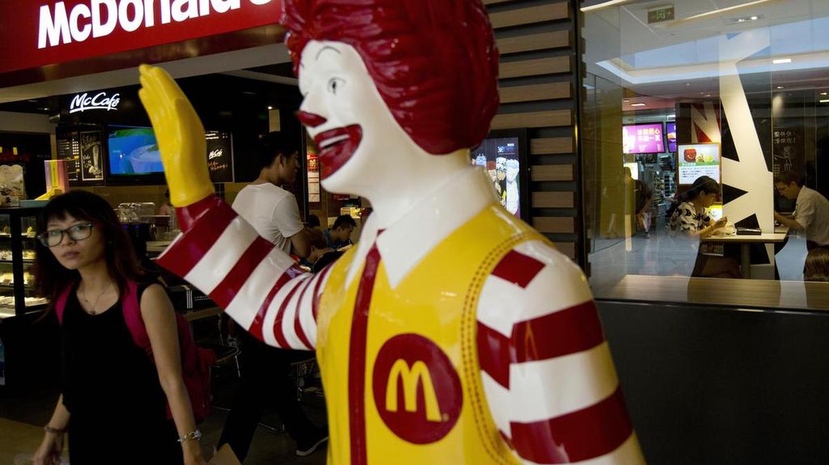En esta foto de archivo un cliente pasa junto a una estatua de Ronald McDonald fuera de un restaurante McDonald en Pekín, China.